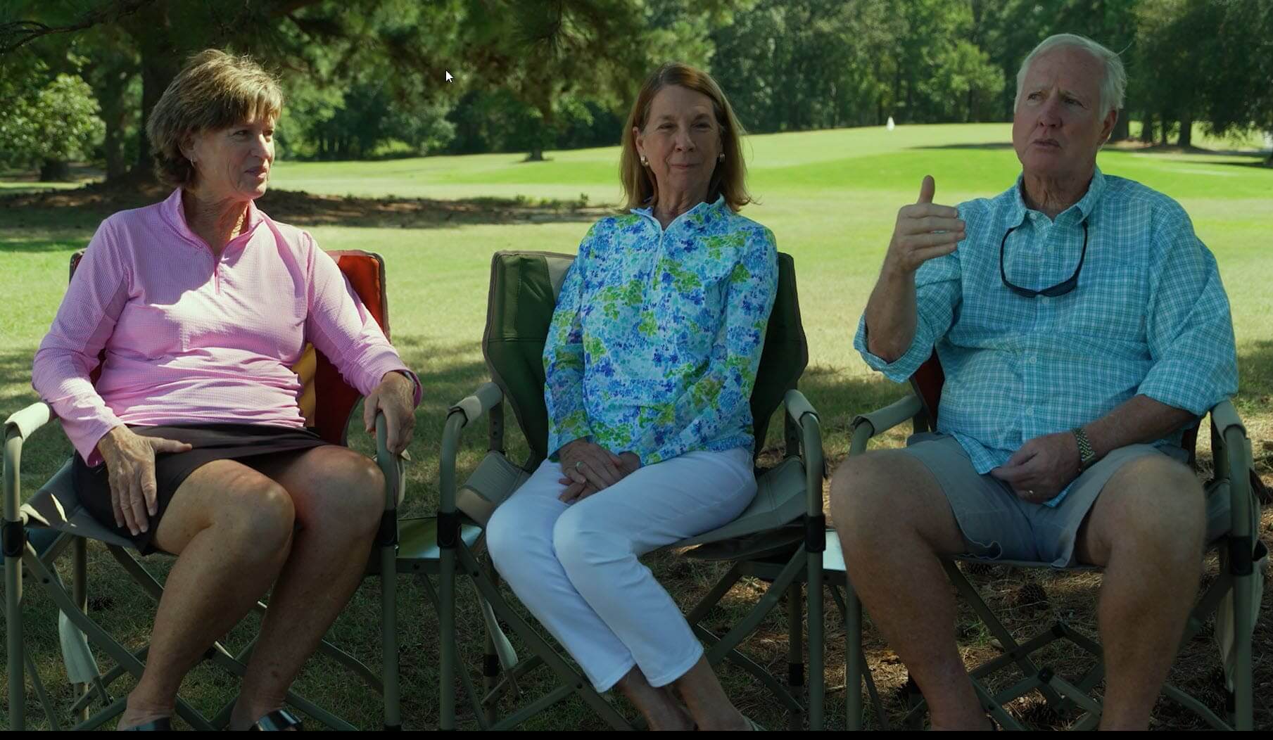 Three people sitting outdoors, talking.