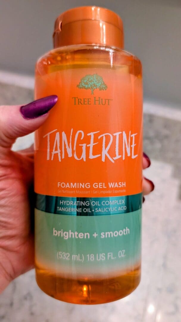 Tangerine foaming gel wash bottle held.